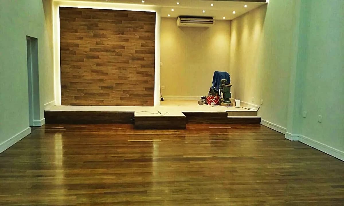 Sala com assoalho de madeira escura e painel de parede em madeira com iluminação LED