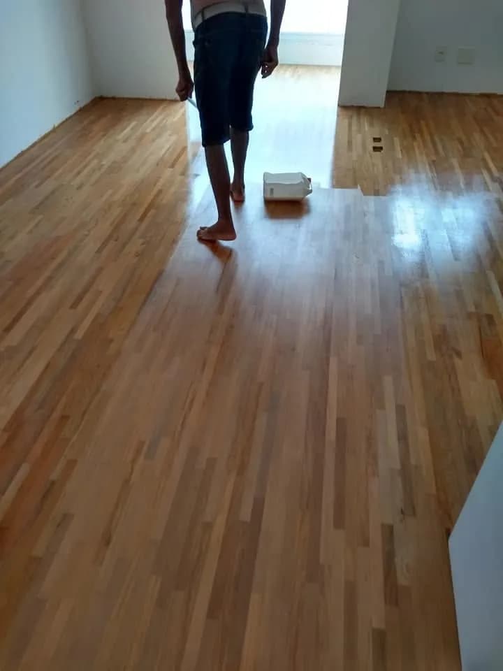 Profissional aplicando sinteco em piso de madeira durante restauração